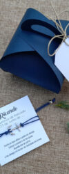 Pulseira em azul marinho com uma âncora, acompanhada de embalagem para lembranças de batizado